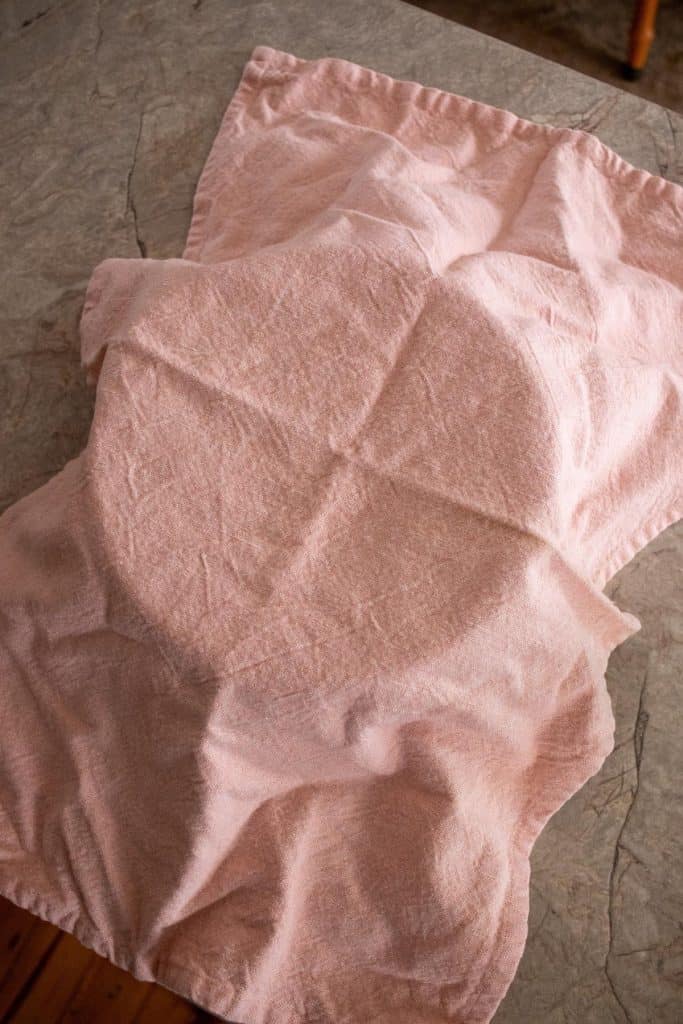 Peach-coloured tea towel covering a glass bowl
