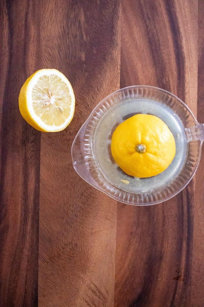 A lemon, sliced in half, on a glass citrus juicer